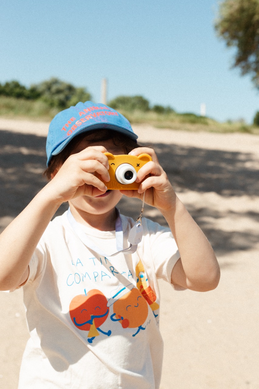 Hoppstar Rookie Kamera mit Bear Honey (Senfgelb) Silikonhülle, Lifestyle Foto Kind mit der Kamera am Strand+