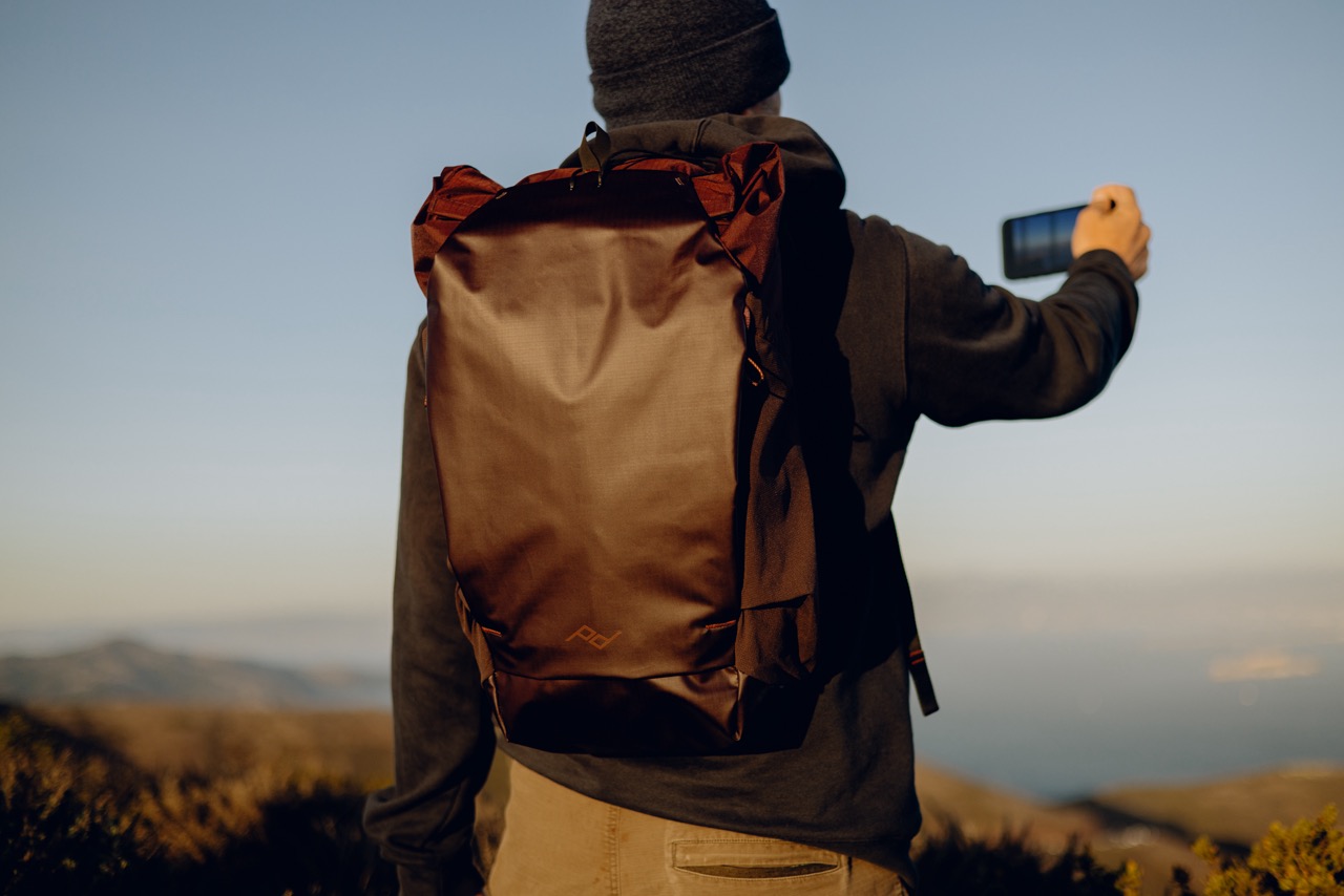 Peak Design Outdoor Backpack mit 25 Litern in der Farbe Lila,  Lifestyle Foto mit Rucksack auf Person  in den bergen