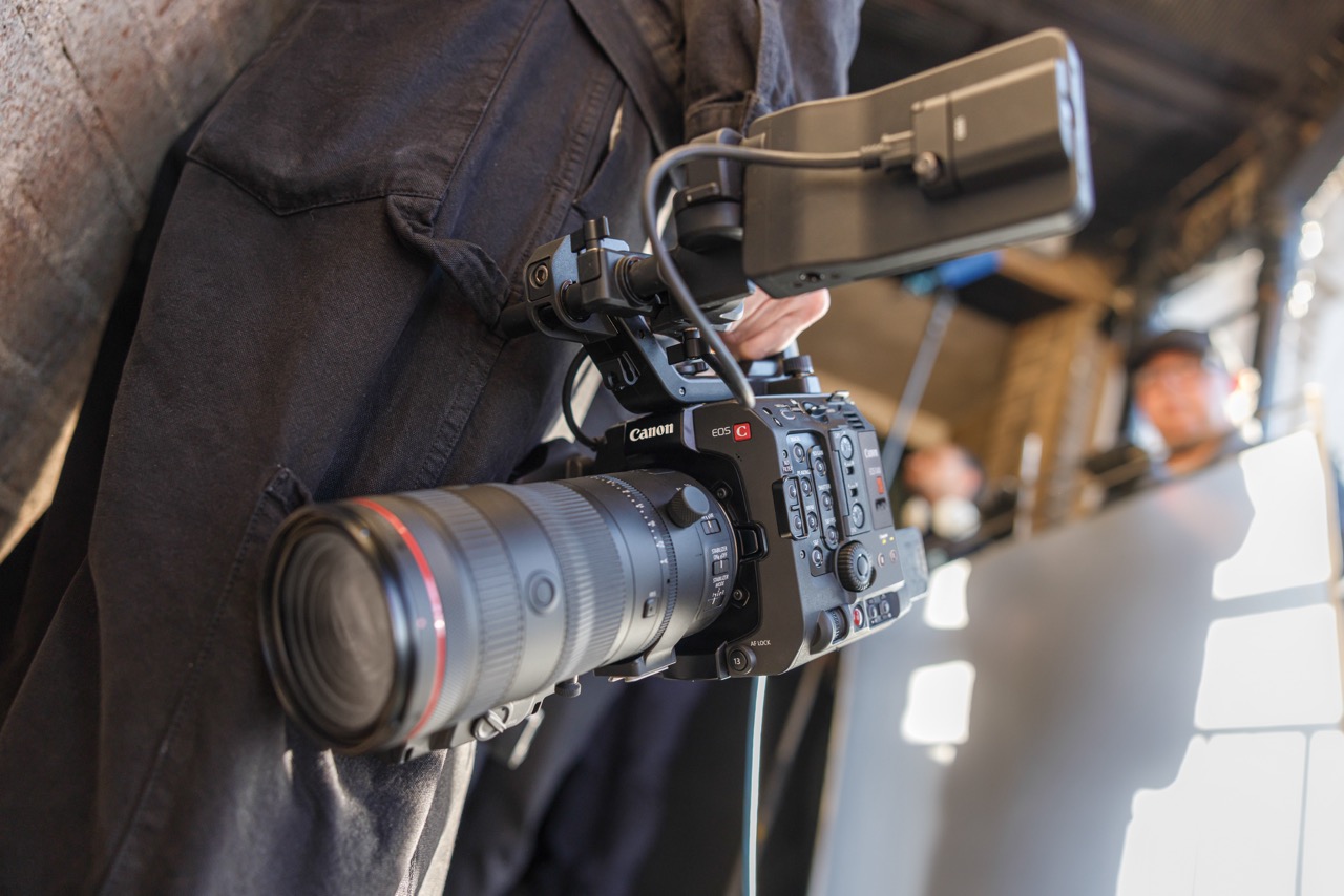 Canon Cinema EOS C400 Videokamera Lifestyle Foto hängend an einer Hose mit Objektiv und Zubehör