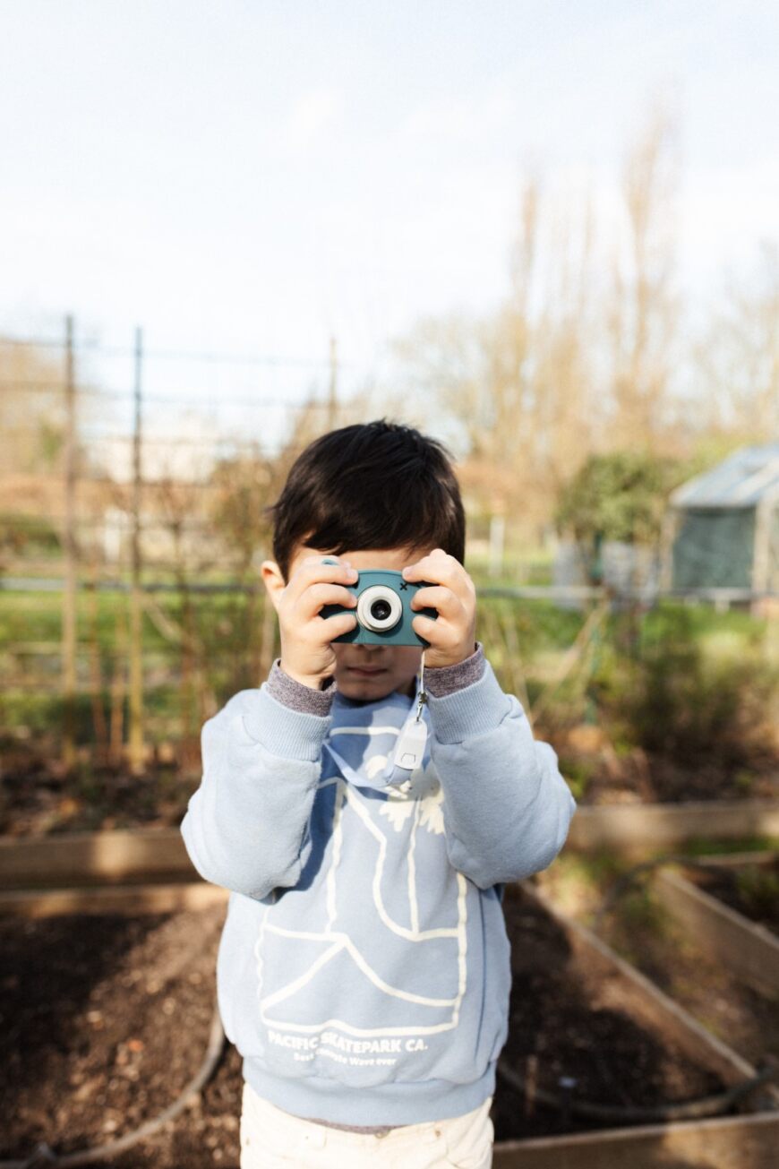 Hoppstar Rookie Kamera mit Bär Yale (blau) Silikonhülle, Lifestyle Foto mit Kind im Garten