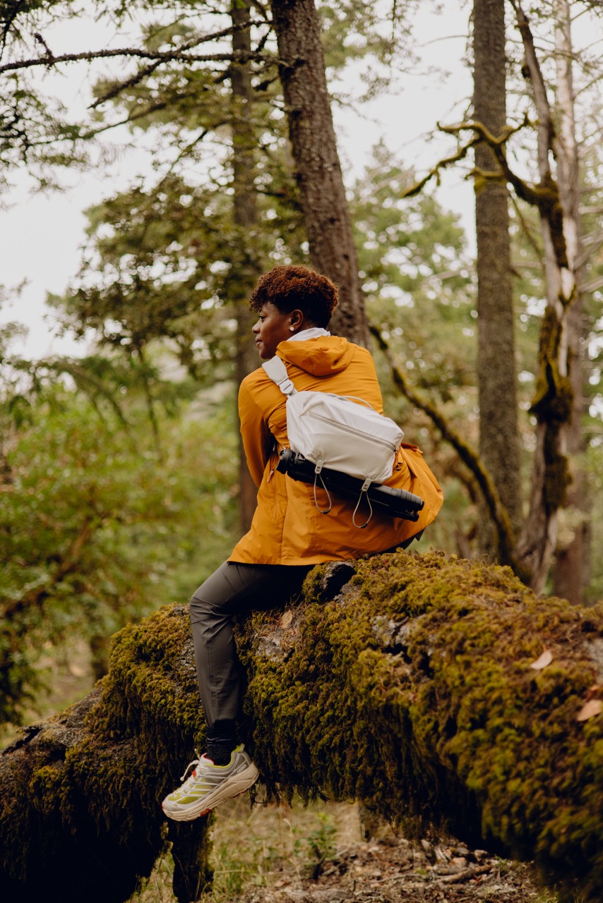 Peak Design Outdoor Sling Umhängetasche mit 7L Volumen in der Farbe Weiss, Lifestyle Foto mit Tasche als Umhängetasche auf Rücken einer Person im Wald